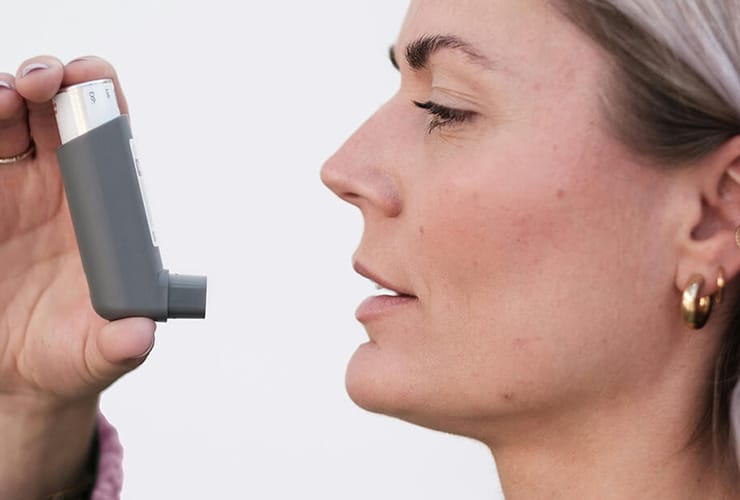 A woman using an asthma pump.